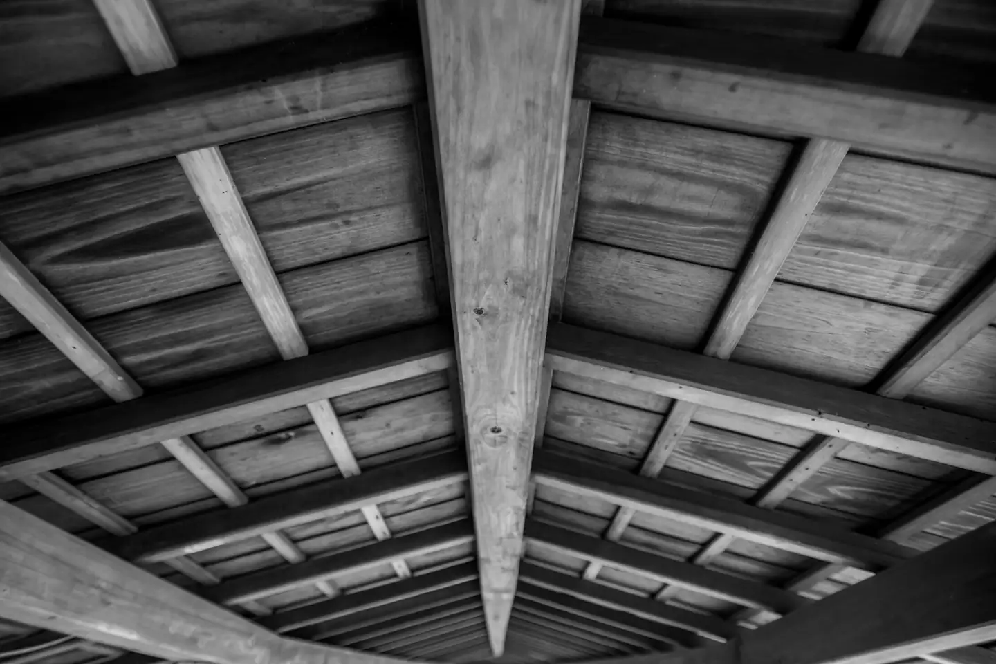 Poutres et solives de bois apparentes vues de dessous, en noir et blanc