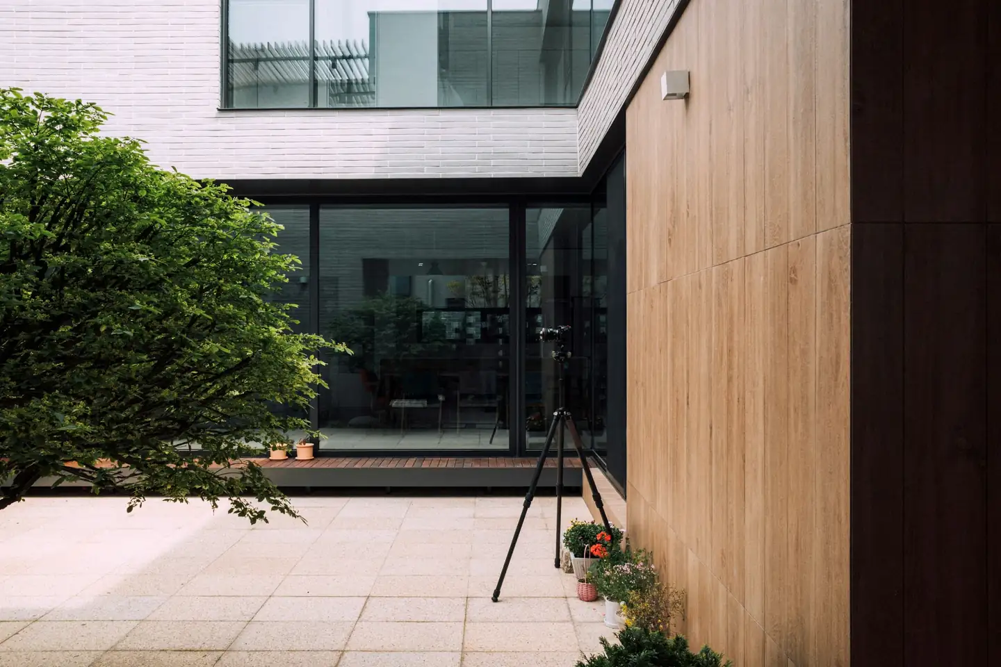 Extension contemporaine en bardage bois et grandes baies vitrées sur une cour pavée