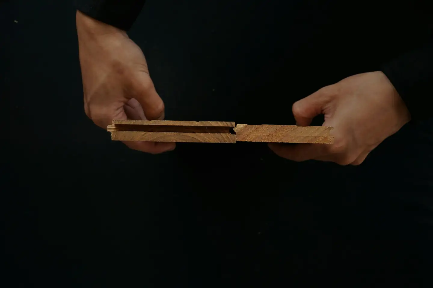 Deux mains qui emboîtent deux lames de parquet par leur rainure et leur languette