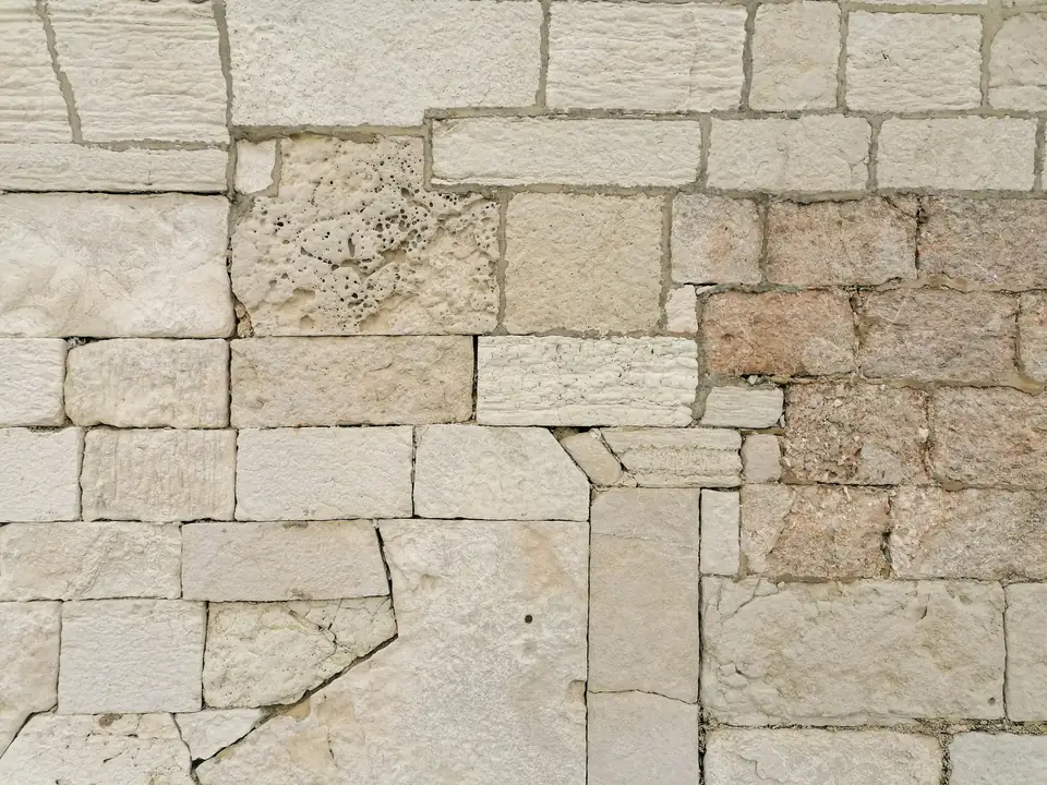 Mur de pierres calcaires claires assemblées en assises irrégulières