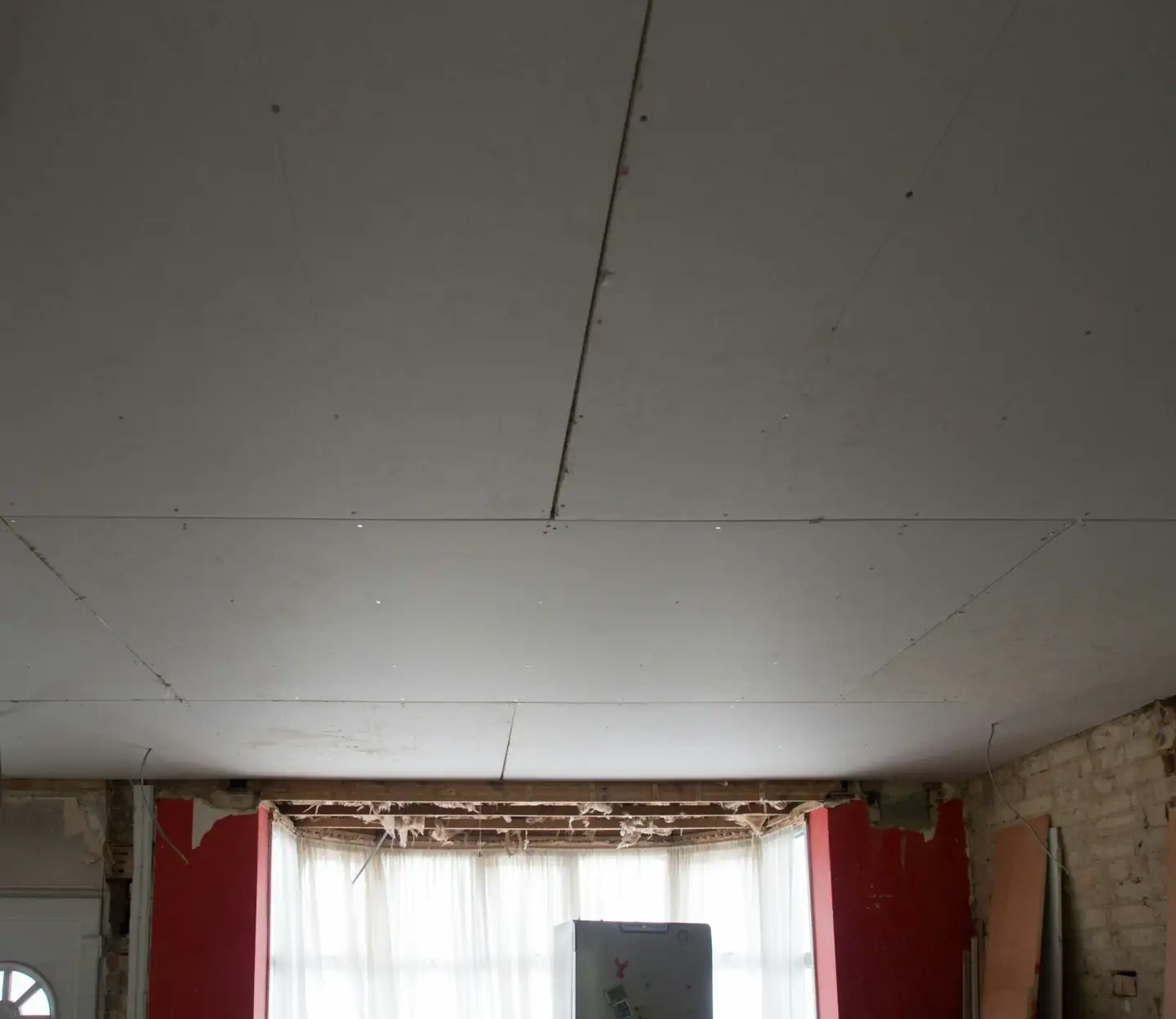 Pièce ancienne en travaux : nouveau plafond en plaques sous une corniche, fenêtre à petits bois